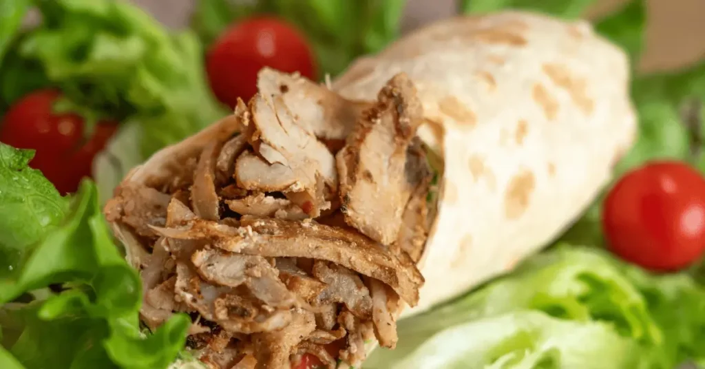 A grilled chicken wrap filled with seasoned chicken strips and surrounded by crisp lettuce and cherry tomatoes, offering a perfect combination for a flavorful grilled chicken wrap recipe.