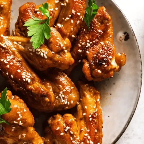 Glazed chicken wings sprinkled with sesame seeds and garnished with fresh parsley, seasoned with a flavorful chicken wing rub recipe.