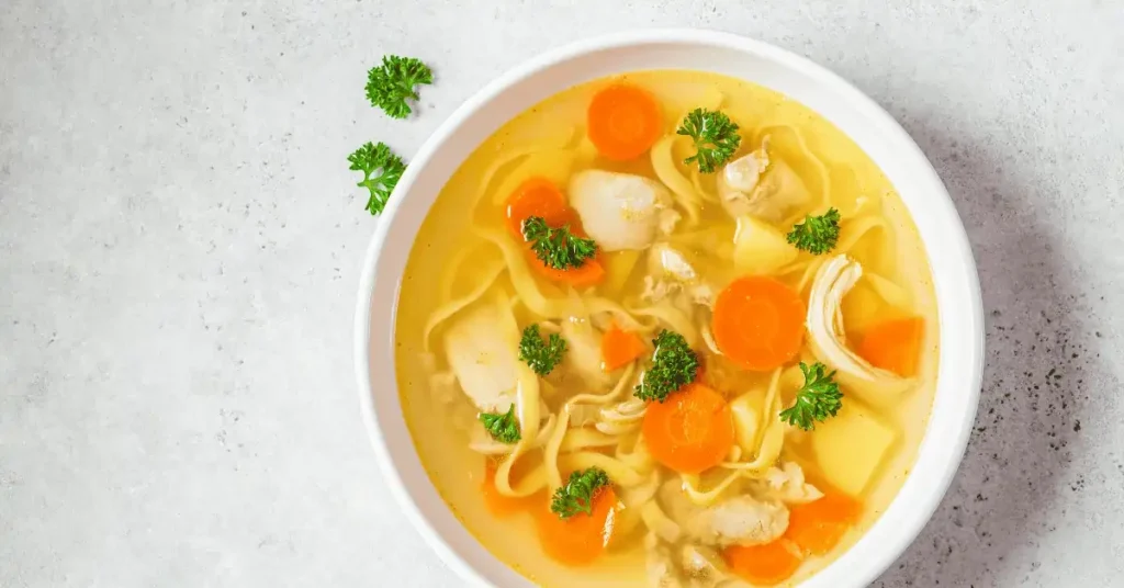 A bowl of Jamaican chicken soup recipe featuring tender chicken, fresh vegetables, and traditional spices.